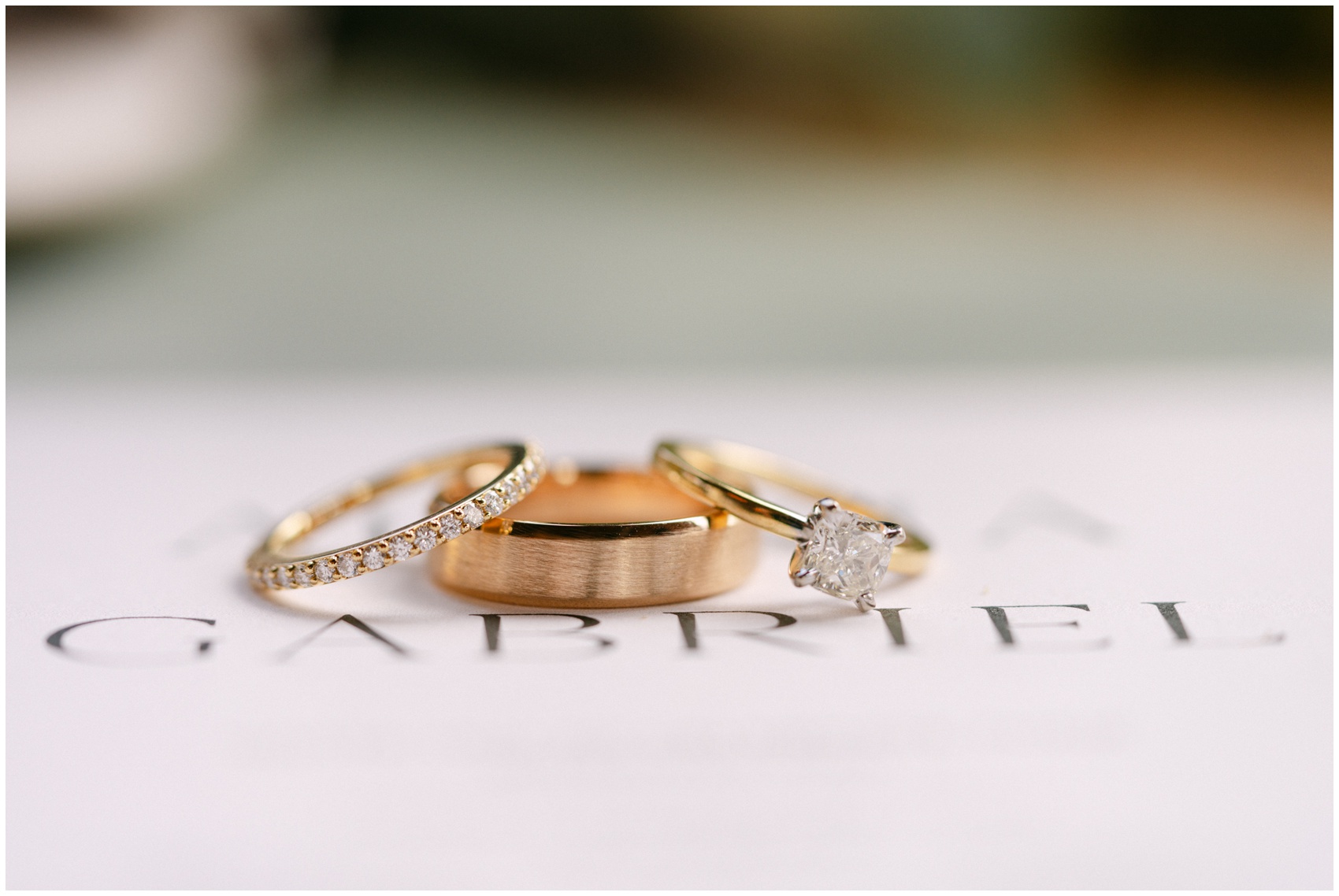 Details of gold wedding rings on an invitation at a Magnolia Grace Ranch Wedding