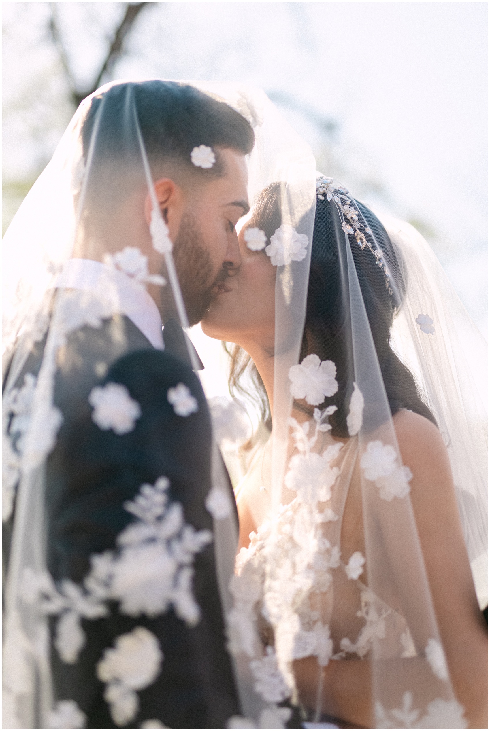 Newlyweds kiss while hiding under the veil at sunset at their Magnolia Grace Ranch Wedding