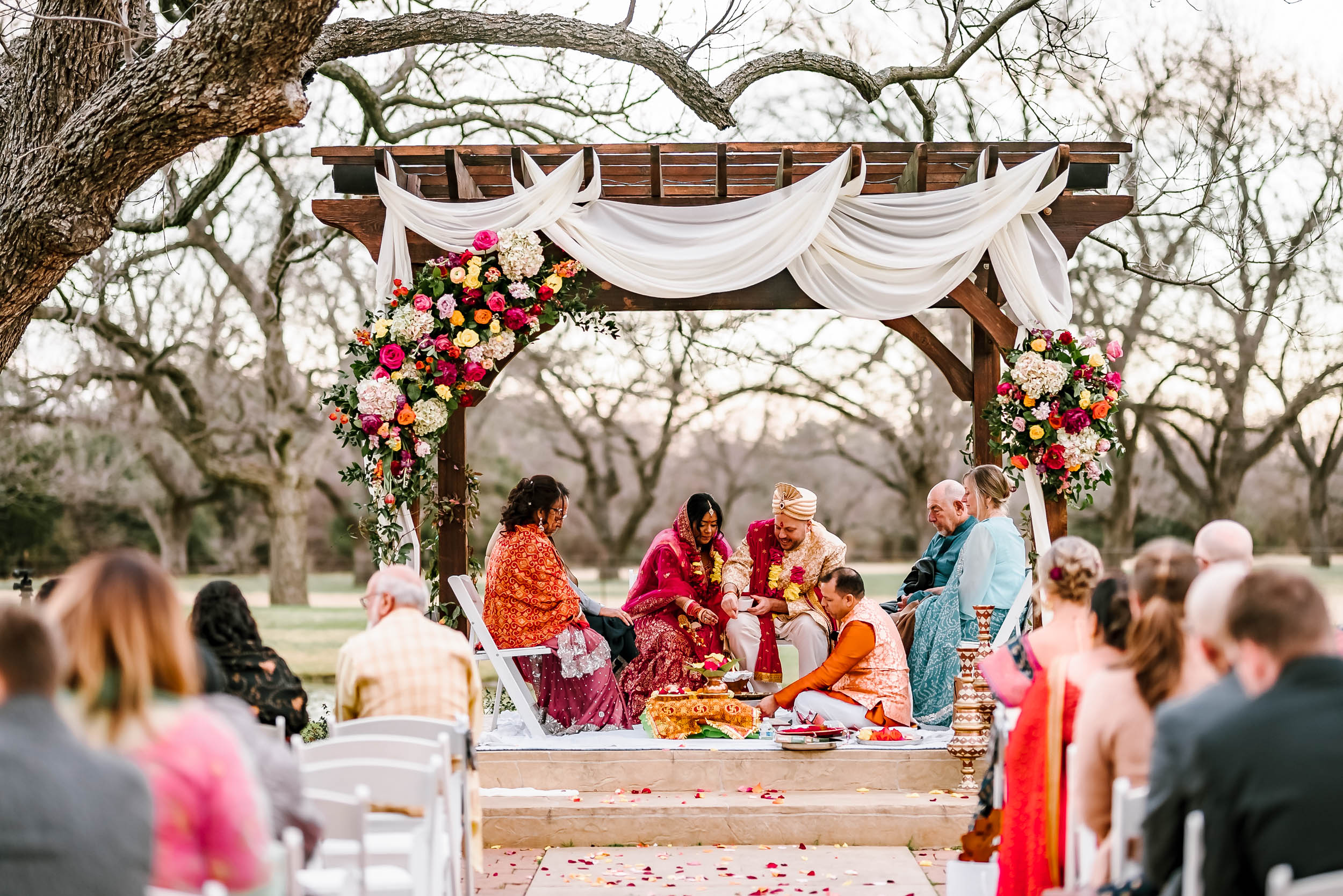 An Indian bride and groom sitting at their traditional ceremony at the beautiful 
The Orchard Event Venue & Retreat - Wedding Venue