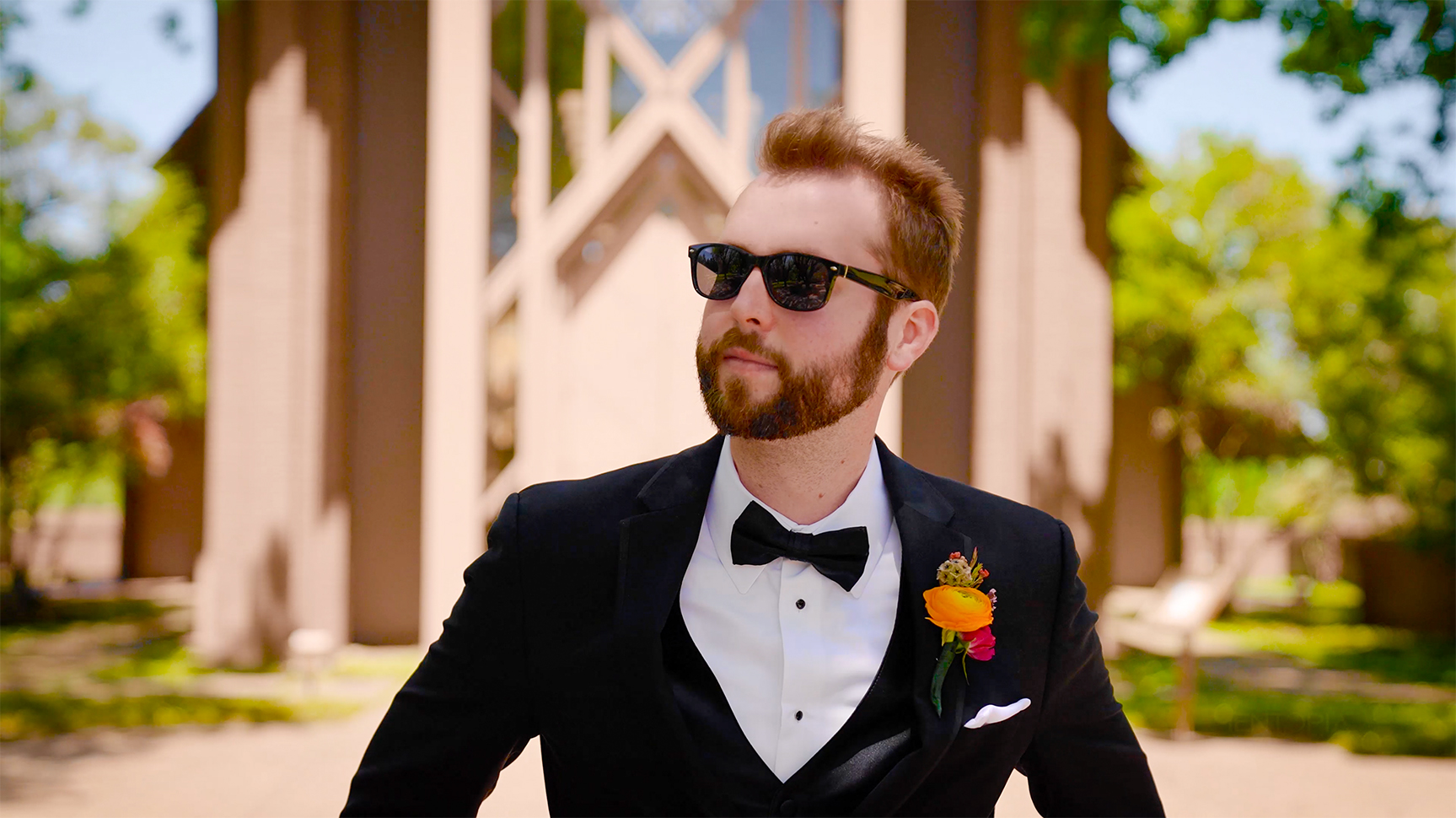 Groom with nice sunglasses posing in front of The Marty Leonard Chapel