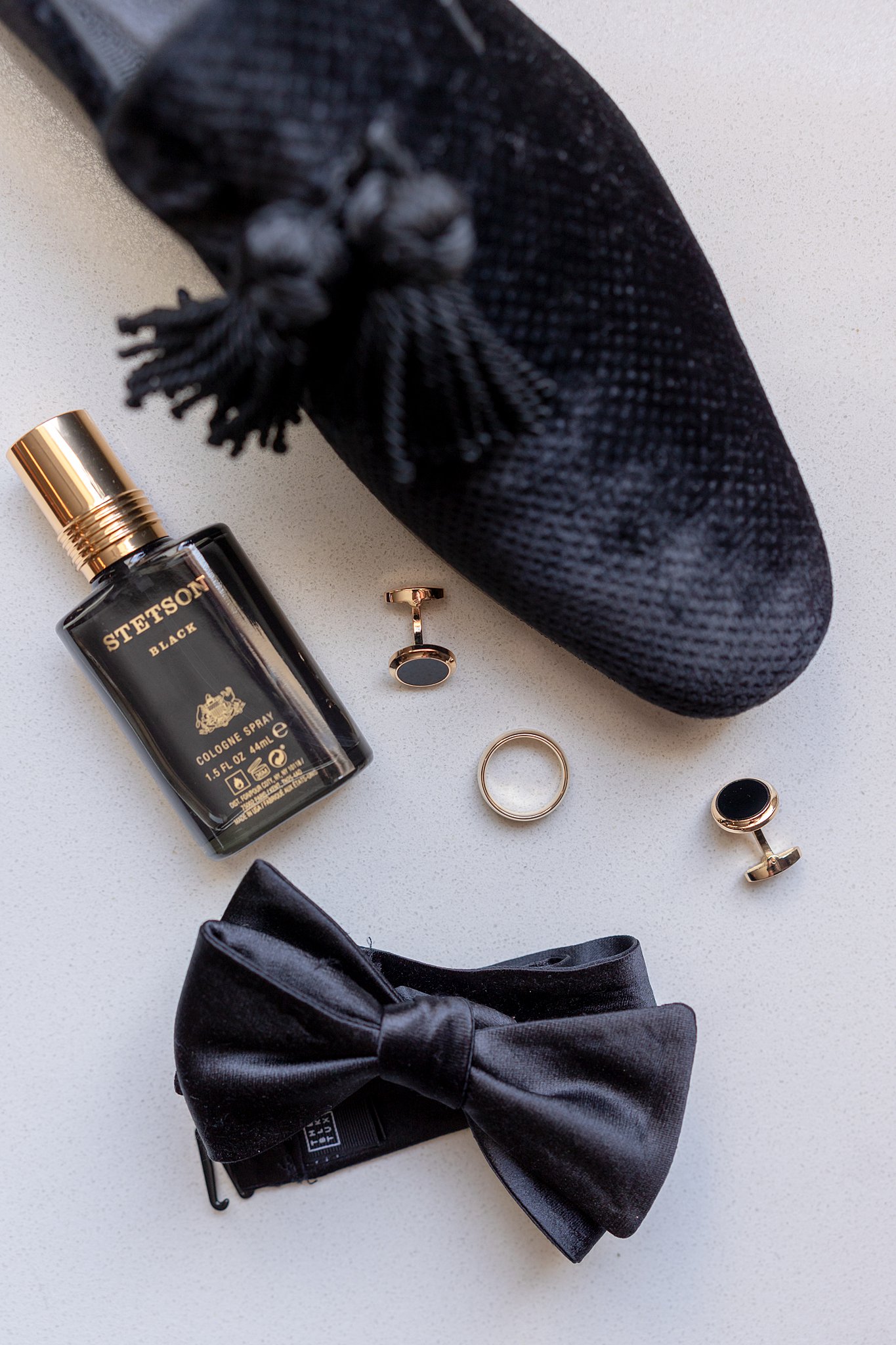 Groom details with black shoe, bowtie, cufflinks and cologne