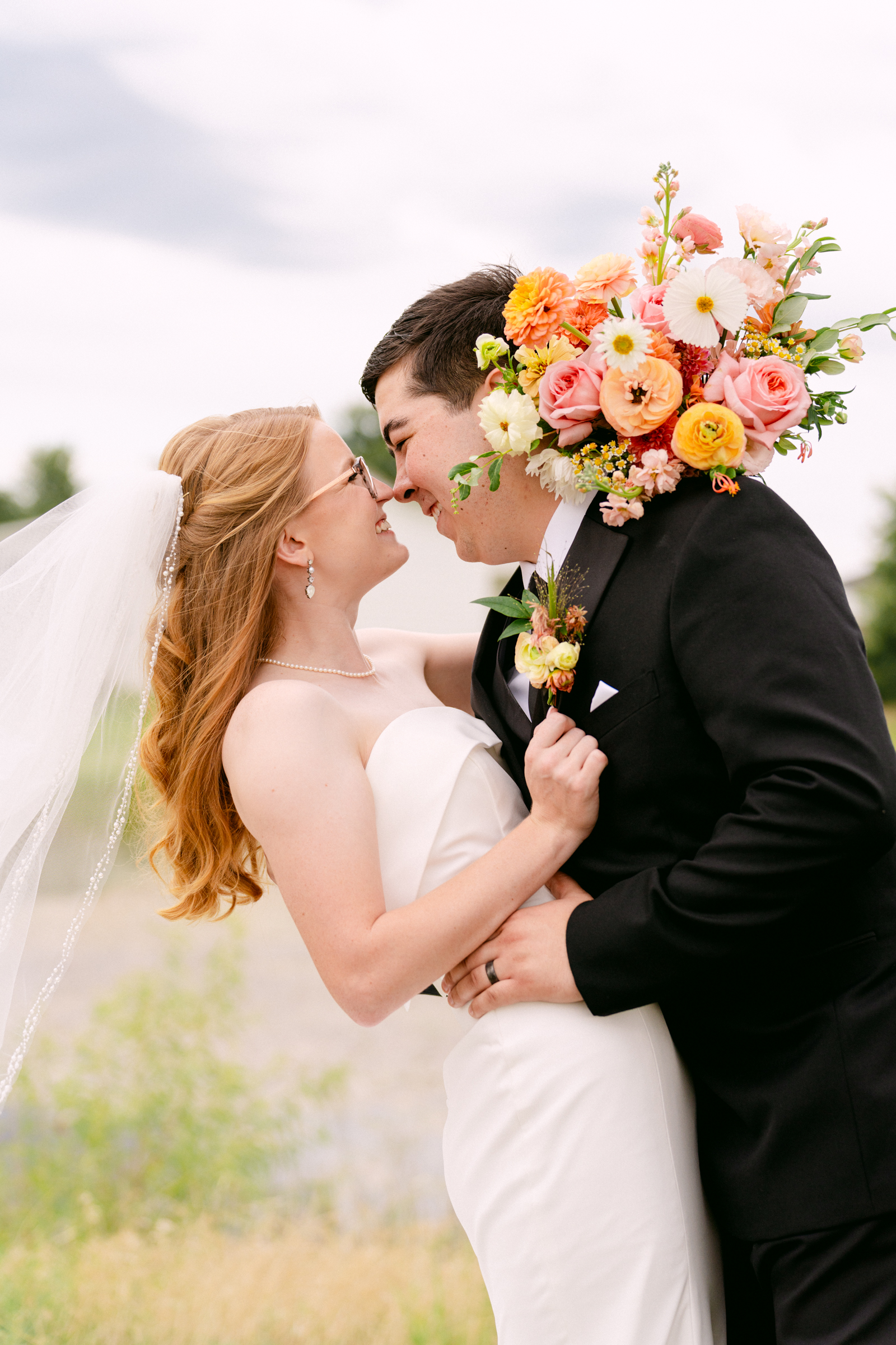 Newlyweds share a happy embrace in a lawn at sunset with a dip at Hera's Haven Wedding Venue