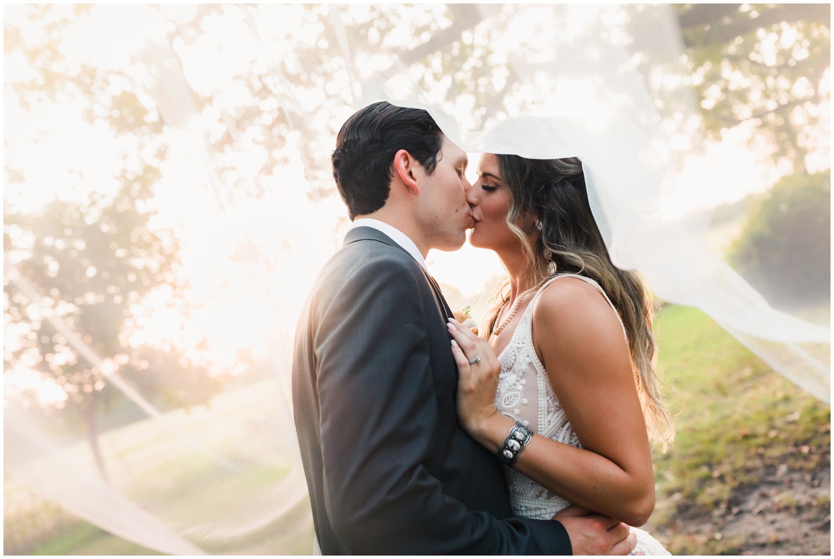 Newlyweds kiss under the veil while standing under a tree at sunset during their Knotting Hill Place Wedding