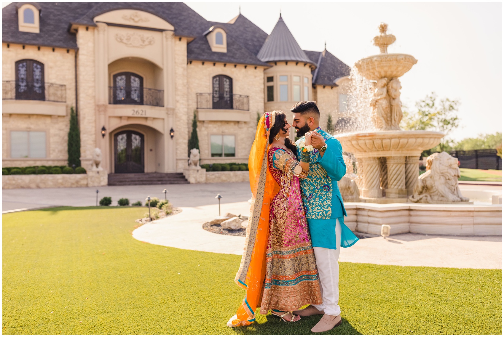 Newlyweds dance by the fountain in traditional dress in the immaculate lawn of their venue