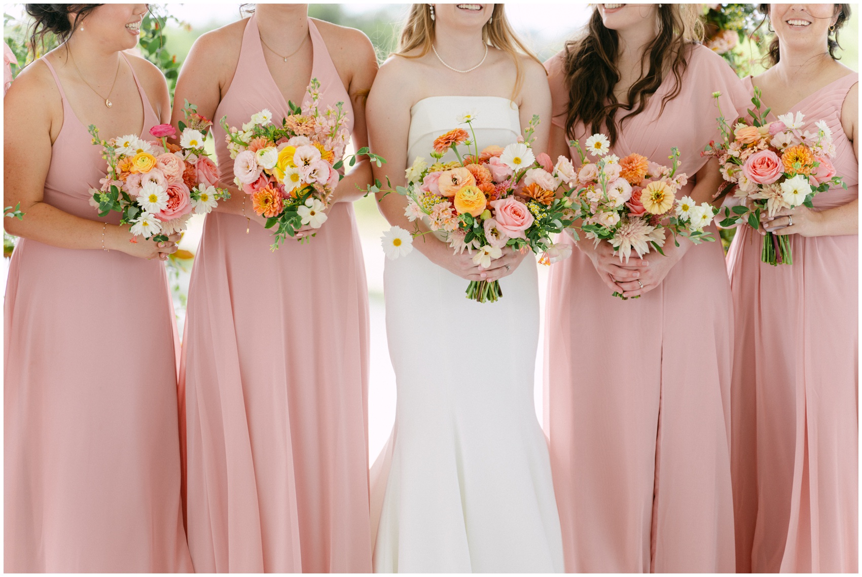 A bride stands with her bridesmaids in pink dresses holding matching bouquets at a Lazy S Hacienda wedding