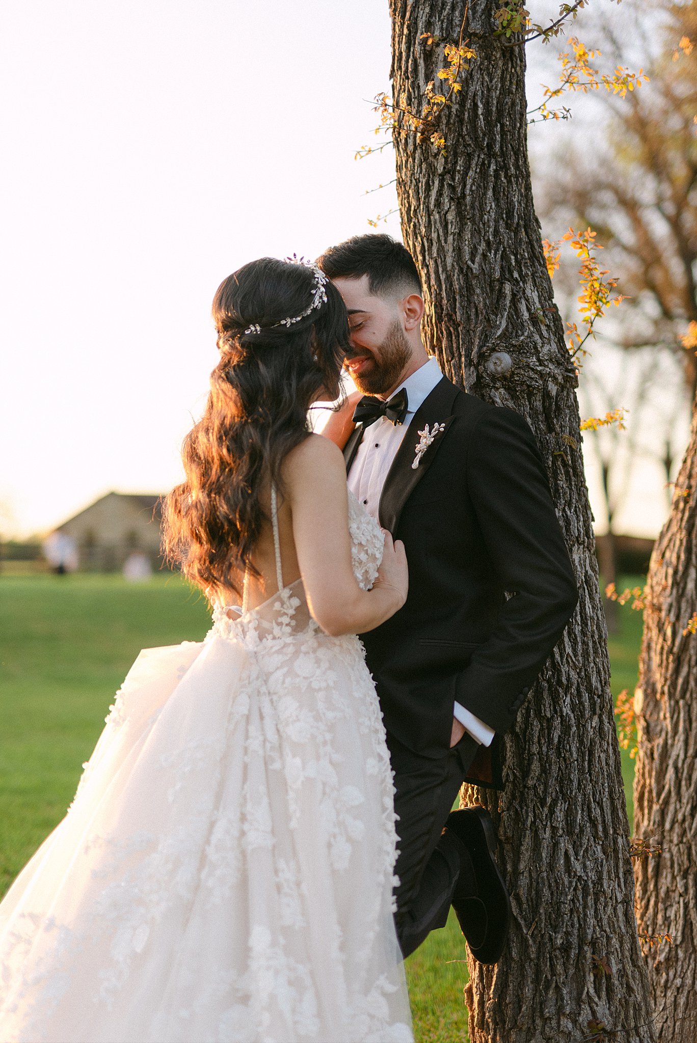 Newlyweds lean against a tree while leaning in for a kiss at their Lone Star Mansion Wedding