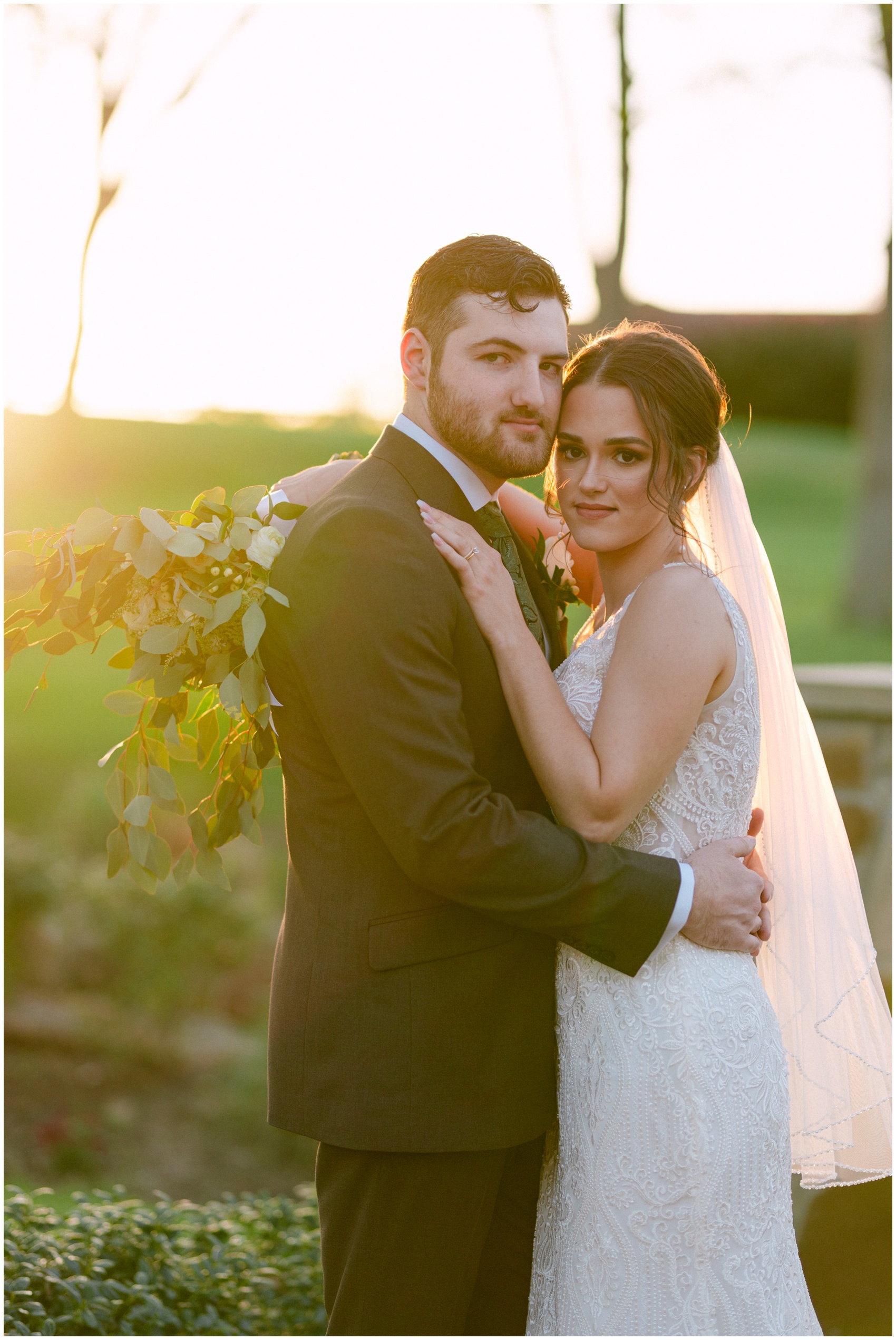 A bride and groom hug and touch cheeks while standing in a garden at sunset at their Rosewood Mansion On Turtle Creek Wedding