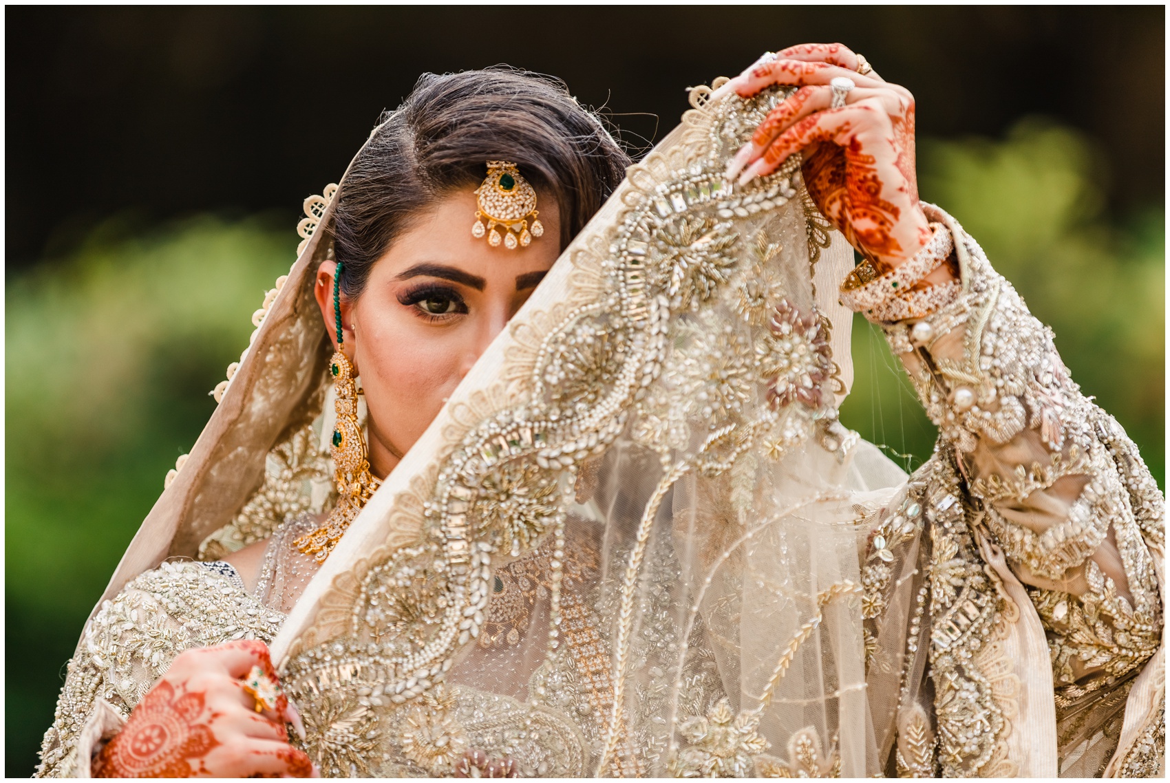 A bride shows off her ornate veil matching her gold dress