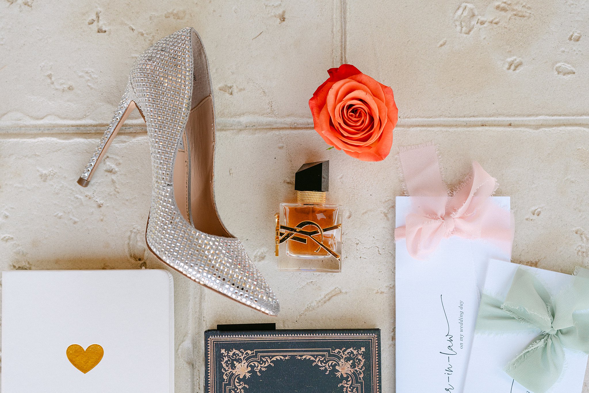 Bridal details on a tile floor with shoe, rose and cologne at The Brooks At Weatherford