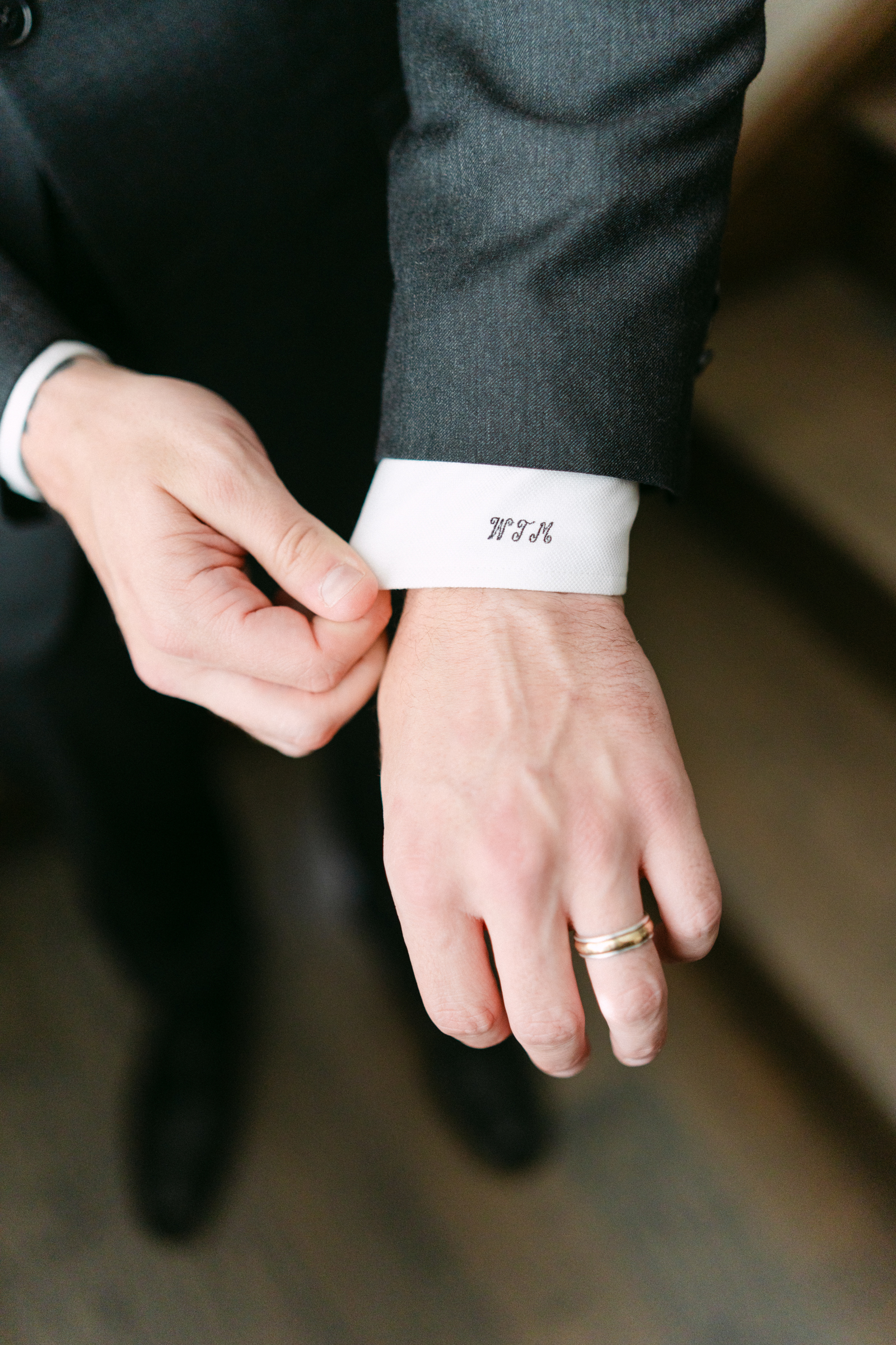 Details of a groom showing off his custom monogram cuffs