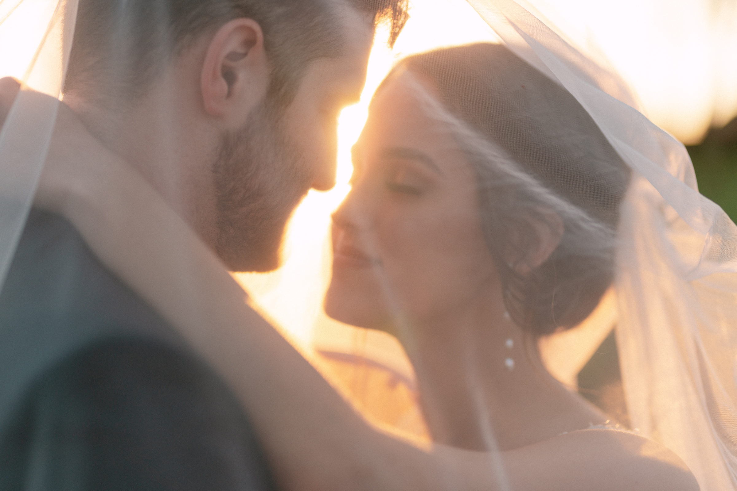 Newlyweds share a kiss during sunset while under the long veil at their The Union House Wedding