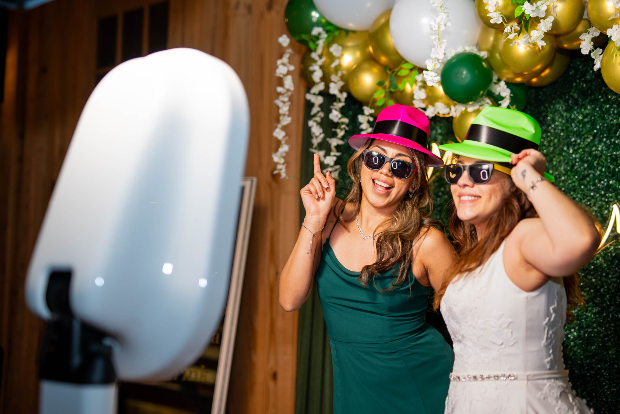 A Bride and her maid of honor having fun and playing with a DFW Photo Booth at a wedding