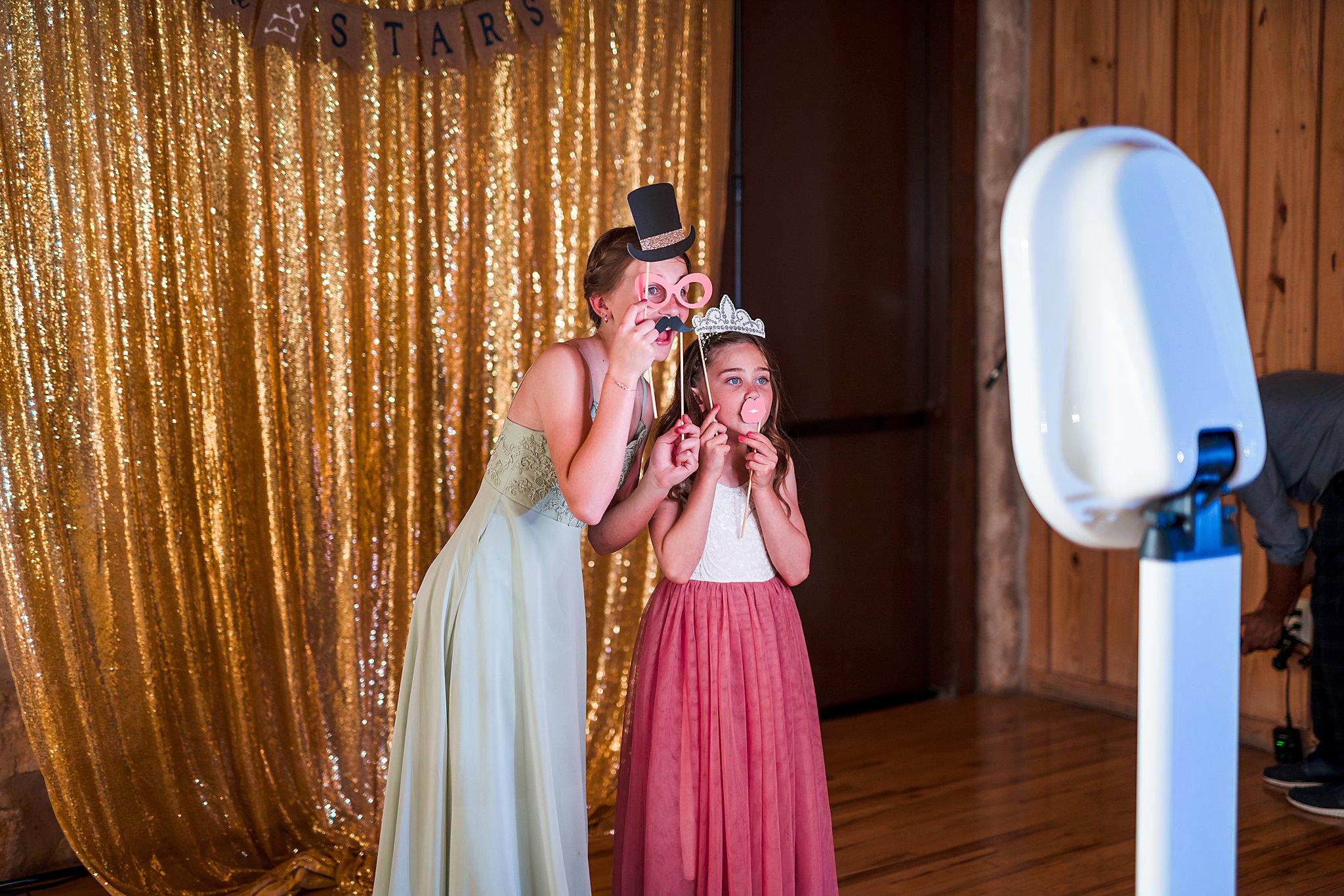 Two young girls play with props in a DFW Photo Booth at a wedding