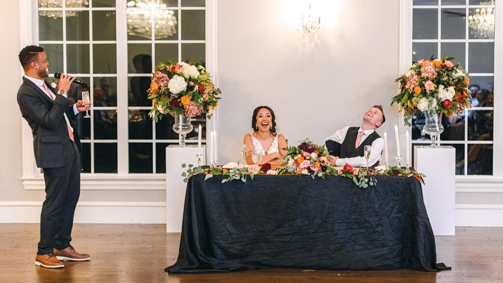 Wedding toast captured while bride and groom laugh during their reception